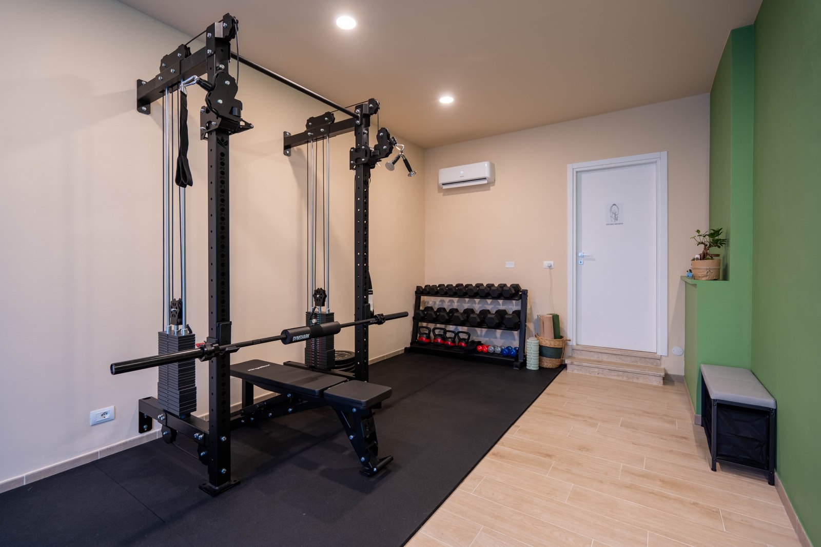 Cable machine, panca, pesi e porta che conduce alla sala osteopatia