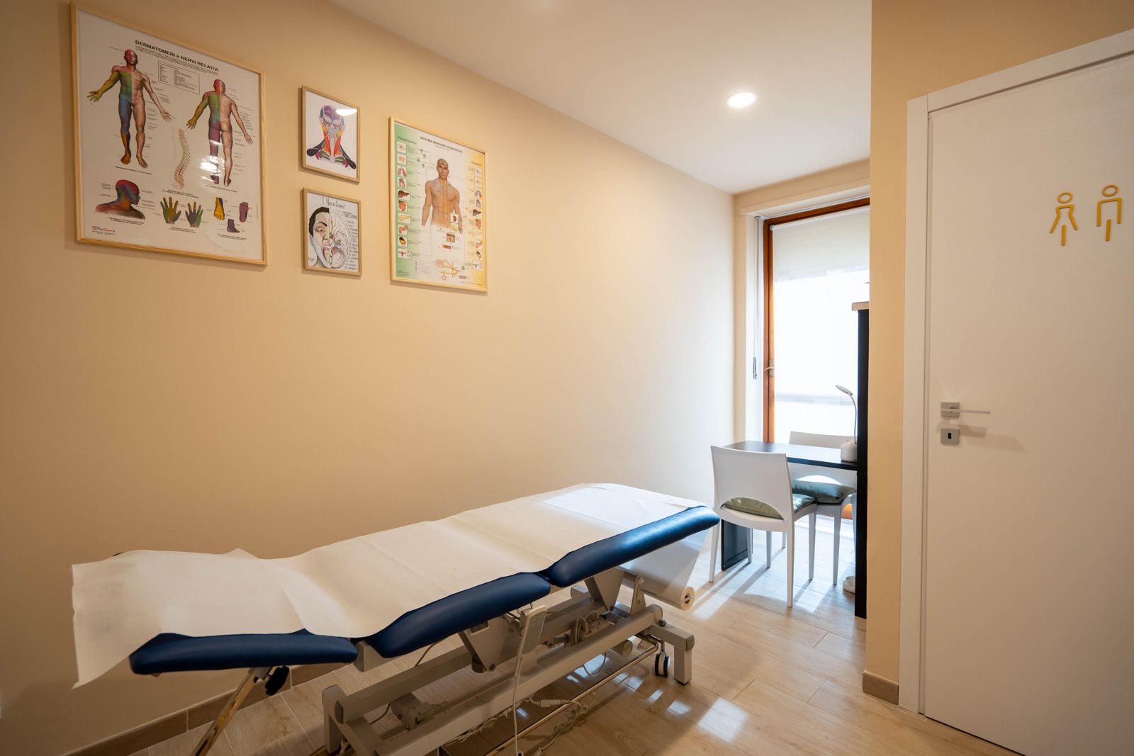 Lettino e tavole anatomiche, con scrivania e portafinestra sul fondo